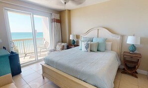 A bedroom with a bed, two bedside tables, a chair, a balcony with a view of the sea, and a sliding glass door. - Coastal Condo 707 | Beachfront! (Panama City)