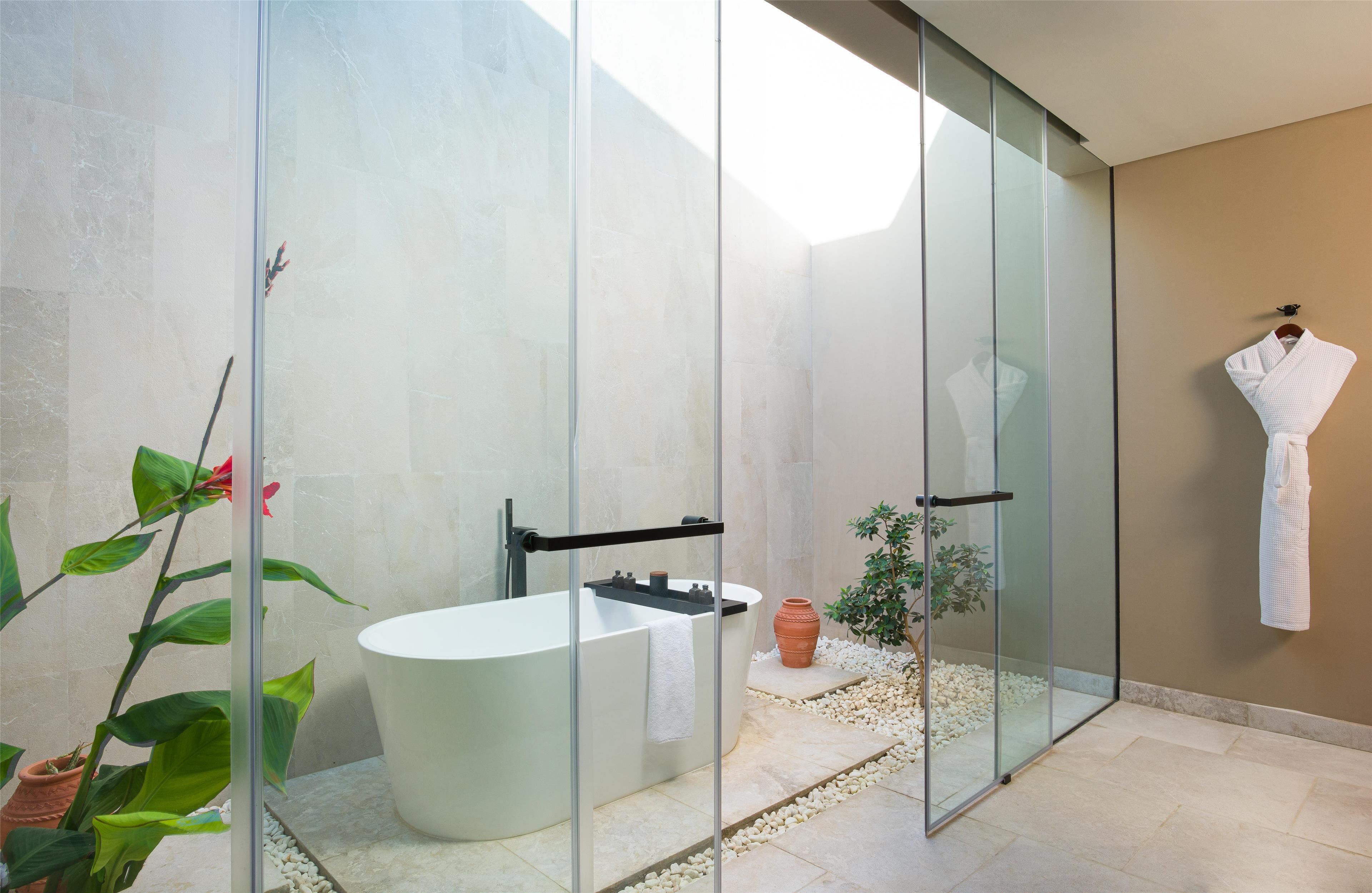 Un baño moderno con una bañera independiente, cabina de ducha de vidrio y una planta en maceta.
