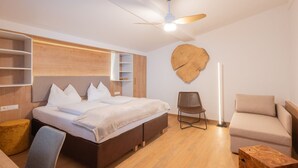 Un dormitorio moderno con cama, una silla, un sofá y una pared de acento de madera.