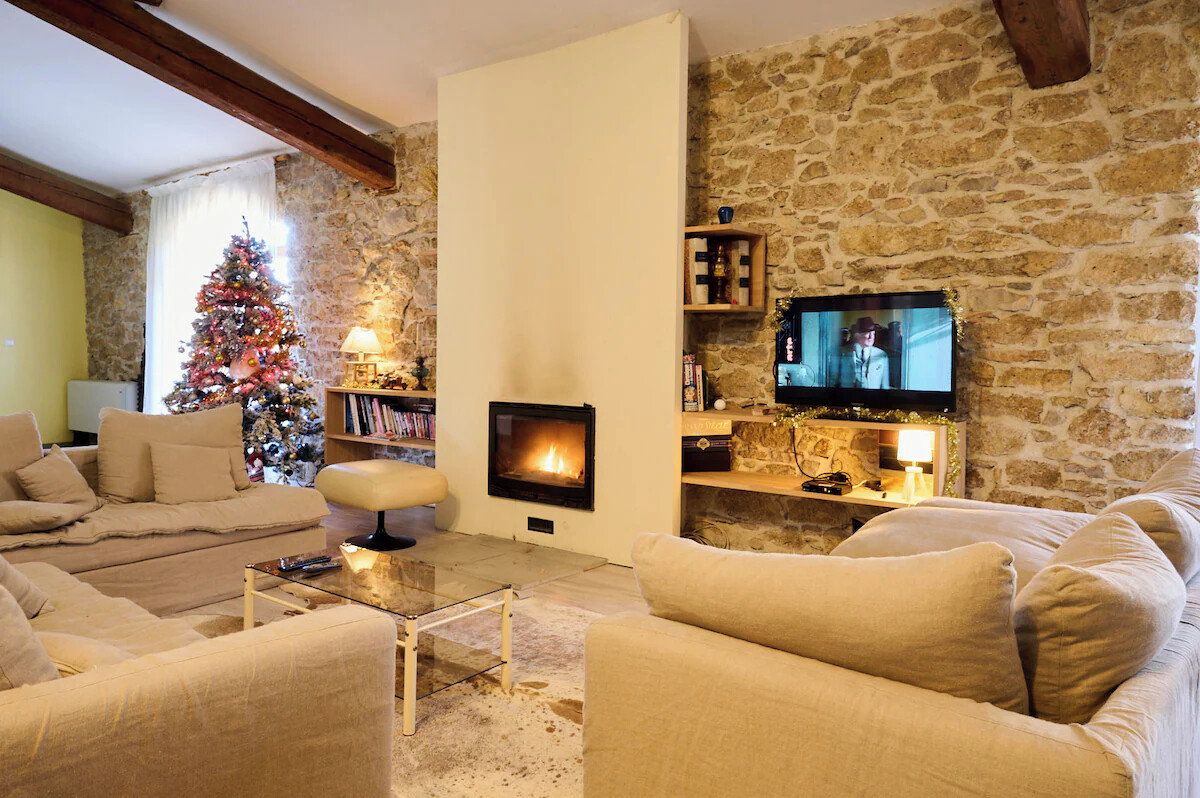 Un salon chaleureux avec une cheminée, un téléviseur et un sapin de Noël.
