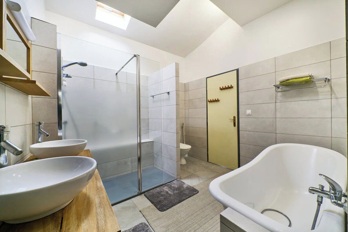 Un baño moderno con bañera, dos lavamanos, ducha e inodoro.