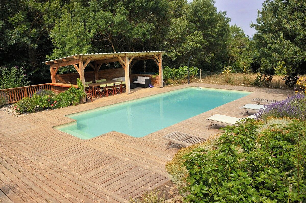 Une terrasse en bois avec une piscine, un espace salon extérieur et une zone abritée.