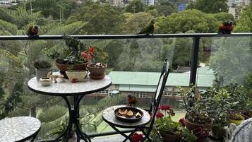 Un balcón con mesa, sillas y plantas en macetas.