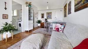 A modern living room with a sofa, a dining table, and a kitchen area in the background. - BAYSIDE BLISS - PRIVATE & TRANQUIL WITH VIEWS, AIR CONDITIONING AND LIFT (Rushcutters Bay)