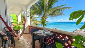 Ein Balkon mit Esstisch, Stühlen, einer Hängematte und Kübelpflanzen.