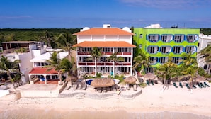 Ein Strandhotel mit mehreren Etagen, einem Poolbereich und einigen Palmen.