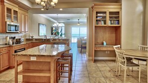 A spacious kitchen with granite countertops, wooden cabinets, and a large island with bar stools.