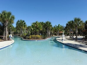 A pool area with palm trees, lounge chairs, and a clear blue sky. - Solterra 52 (Davenport)
