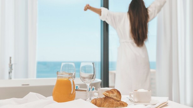 A breakfast setup with a jug of orange juice, a glass of water, a croissant, and a cup of coffee on a table. - Senator Gandia Hotel (Gandia)