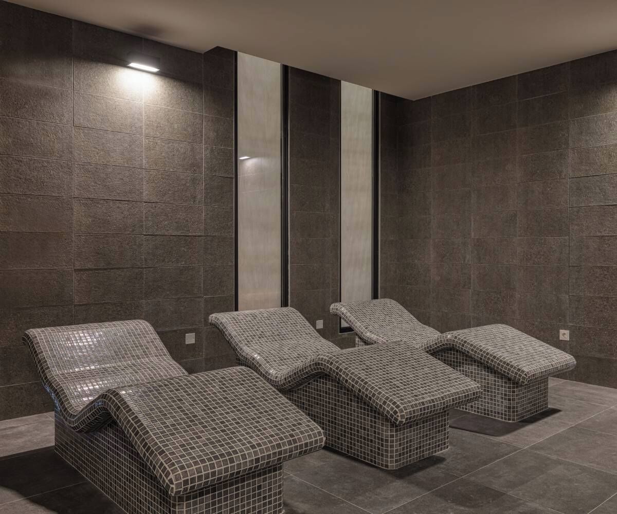 Un cuarto de spa con cuatro sillones reclinables y un espejo grande en la pared.