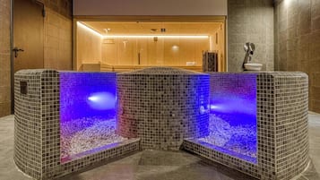 Un área de spa con dos tinas de piedra climatizadas, un mostrador de recepción de madera y una pared de azulejos.