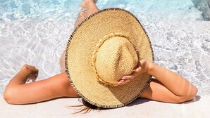 A person lying on a beach with a straw hat, near a pool with clear blue water. - Senator Gandia Hotel (Gandia)