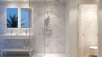 Een moderne badkamer met een douche met glazen wand, marmeren tegels en een ingebouwd wastafelmeubel.