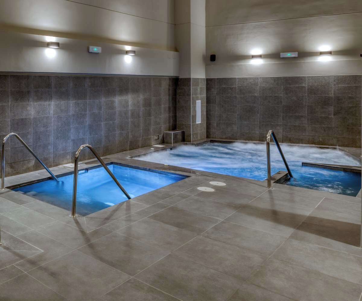 A spa area with two hot tubs and a tiled floor.