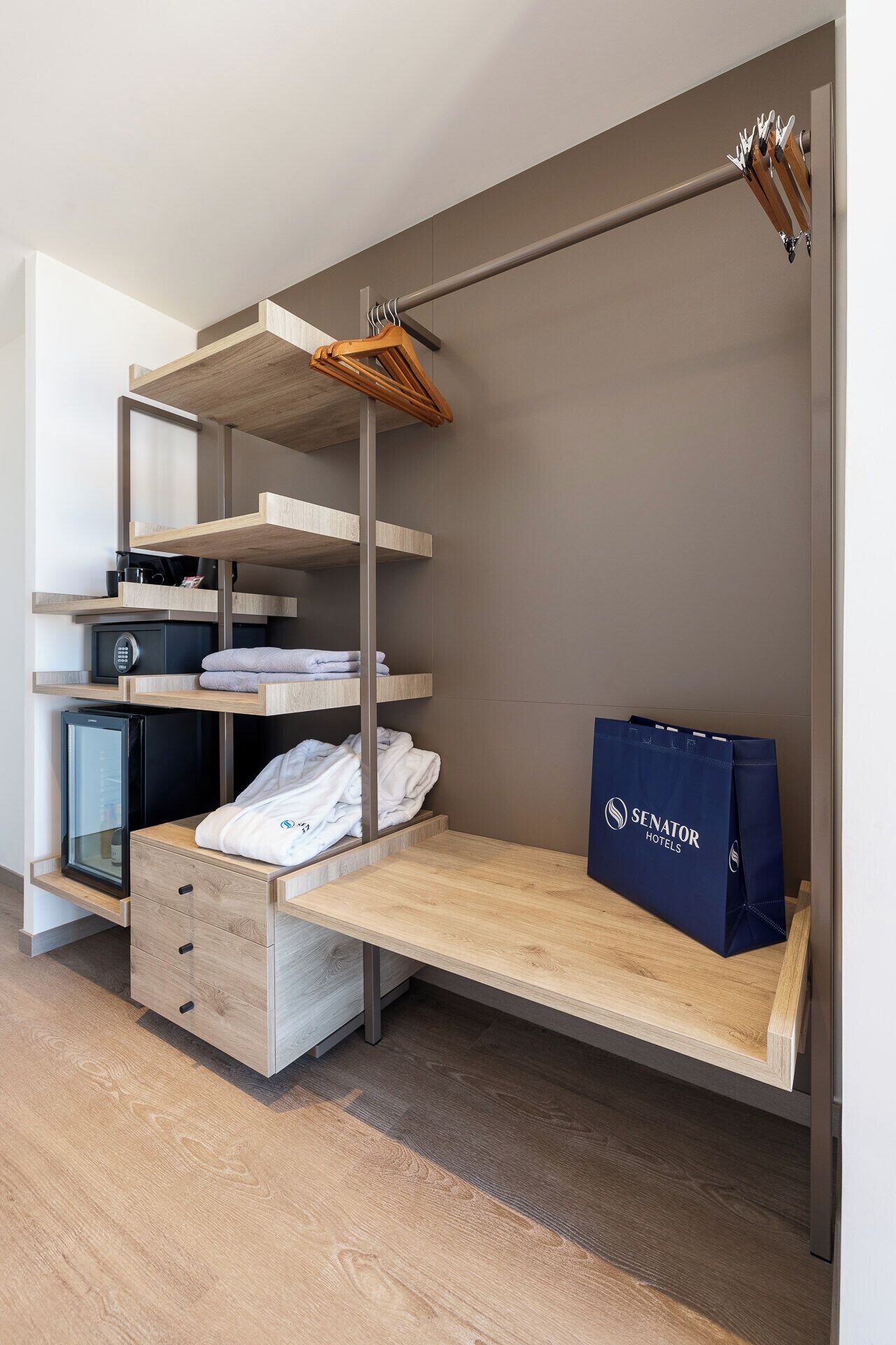 A compact hotel room with a bunk bed, a desk with a computer, a microwave, and a minibar.
