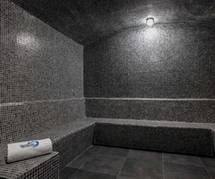A tiled room with a bench and a towel labeled "Senzia".