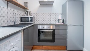 Eine kleine Küche mit Mikrowelle, Backofen und Kühlschrank.