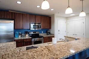 A modern kitchen with granite countertops, stainless steel appliances, and wooden cabinets.