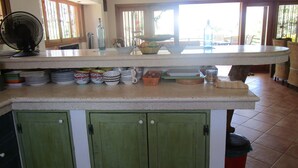 A kitchen with a central island, green cabinets, and a fan. - Beautiful home with ocean views (Playa Samara, Nicoya)