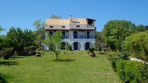 A two-story house with a tiled roof, arched windows, and a balcony.