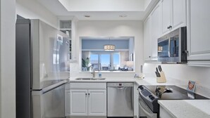 Una cocina moderna con armarios blancos, electrodomésticos de acero inoxidable, lavavajillas y estufa.