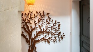A hallway with a textured wall, a decorative tree mural, and a hanging light fixture.