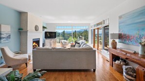 Un salón amplio con chimenea, asientos cómodos y un gran ventanal con vistas panorámicas.