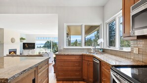 Una cocina moderna con encimeras de granito, gabinetes de madera y estufa de acero inoxidable.