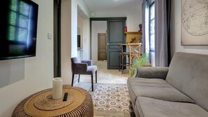 Una sala de estar moderna con un sofá gris, un televisor montado en la pared, una mesita de mimbre y una alfombra estampada.