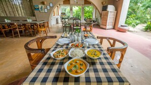 Un coin repas avec une nappe à carreaux, de nombreux plats et des chaises en bois.