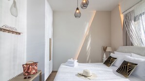 Un dormitorio ordenado con cama, mesitas de noche e iluminación colgante.