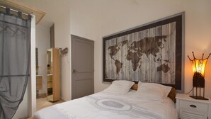A bedroom with a large bed, a wooden headboard with a world map, a bedside lamp, and a wardrobe.