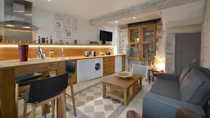 A compact living space with a kitchenette, a sofa, a dining table, and a washing machine.