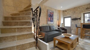 A stone staircase leading to a living area with a sofa, coffee table, and a fish hanging on the wall.