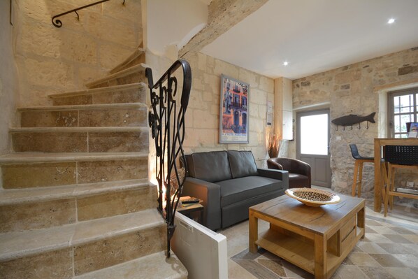 A stone staircase leading to a living area with a sofa, coffee table, and a fish hanging on the wall.