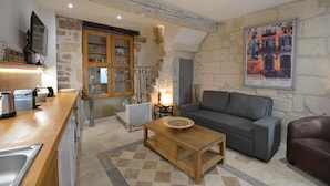 A cozy living area with a sofa, a coffee table, and a kitchen area with a sink and stove.