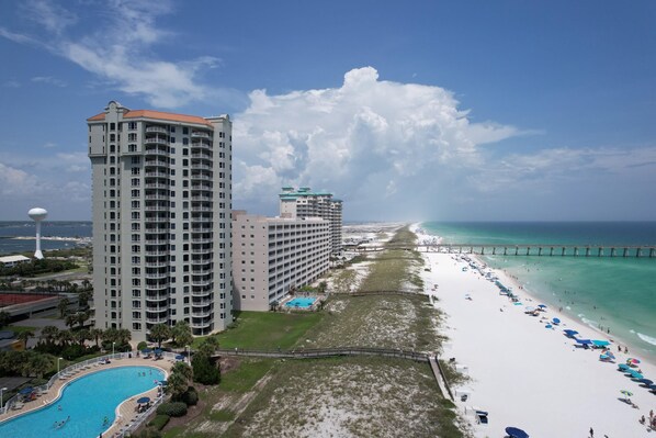 A beachfront hotel with a swimming pool, beach umbrellas, and a pier in the background. - Your PooleParadise (Navarre Beach)