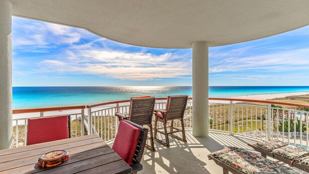 Ein Balkon mit Blick auf den Ozean, Holzmöbel und ein Poolbereich.
