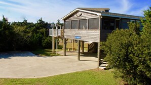 A small, single-story building with a covered porch, a sign indicating a parking area, and a concrete driveway. - SALVO STARRY NIGHTS Beach House Bliss 5 min walk to beach (Salvo)