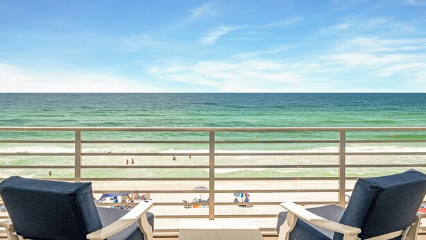Ein Balkon mit Blick auf den Ozean, Strandstühle und Sonnenschirme.