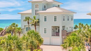Ein mehrstöckiges Anwesen direkt am Strand mit hellblauer Fassade, mehreren Fenstern und einem Balkon.