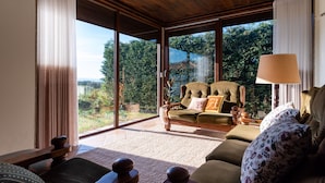 A spacious living room with a large sliding glass door leading to a garden, a comfortable sofa, and a wooden coffee table.