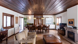 A spacious living room with a wooden ceiling, a fireplace, a dining area, and a television.