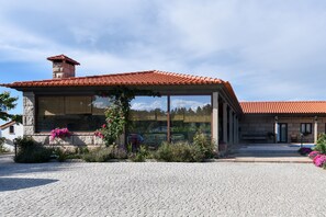 A stone building with a red-tiled roof, large windows, and a cobblestone driveway. - Feel Discovery Maçã Douro (Armamar)