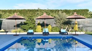 A swimming pool with three umbrellas and lounge chairs.