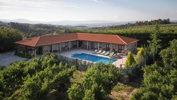 Relax by the outdoor pool surrounded by a beautiful garden and patio area with scenic views of the surrounding landscape.
