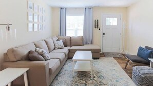 A modern living room with a sectional sofa, a white coffee table, and a patterned rug. - Room for Everyone with 2 Townhomes and 6 Bedrooms! (Candler)