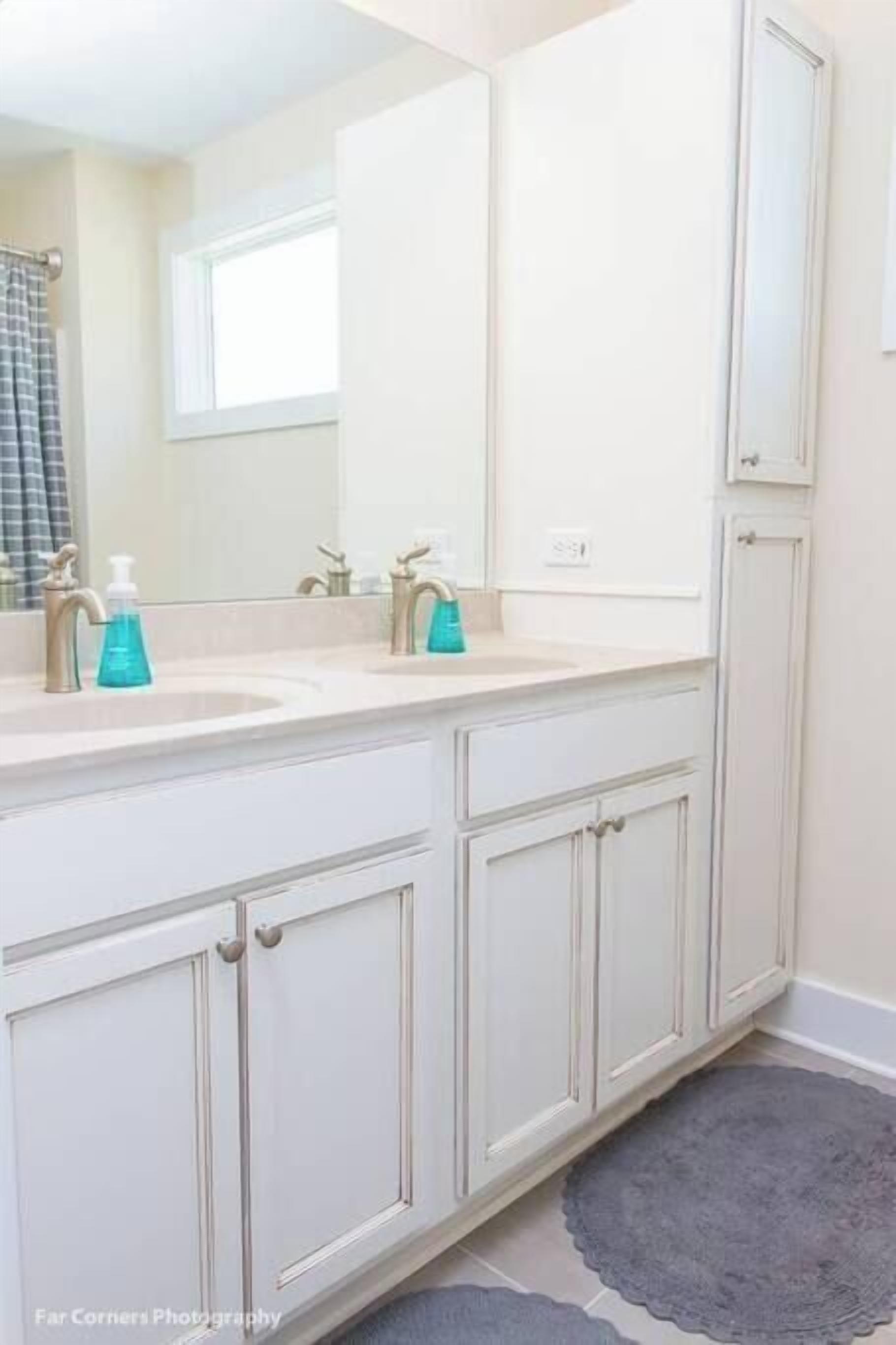 Une salle de bain avec deux lavabos, un miroir et une fenêtre.