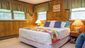 Ein Schlafzimmer mit einem großen Bett, zwei Nachttischlampen, einem Holzkopfende und einer Steppdecke.