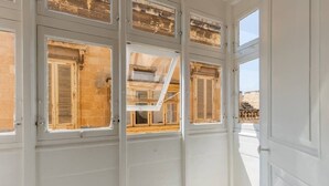 Une pièce aux murs blancs et dotée de nombreuses fenêtres, dont certaines sont équipées de volets.